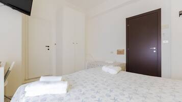 A hotel room with a bed, a wardrobe, a door, and a flat-screen TV.