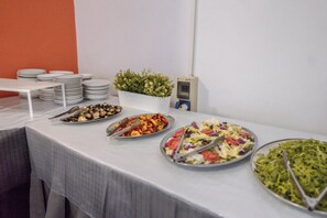 A buffet table with various dishes, a potted plant, and a wall-mounted device.