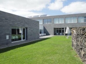 Un edificio moderno con fachada de piedra, ventanas amplias y un césped cuidado.