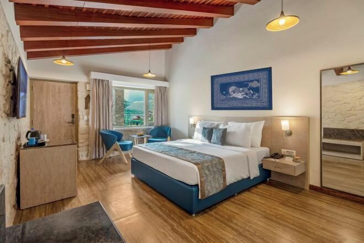 A bedroom with a bed, bedside table, and a window with curtains.