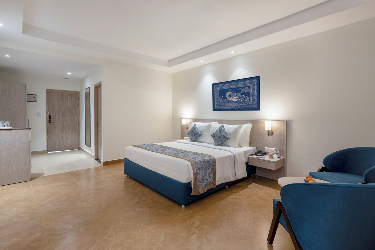 A modern hotel room with a large bed, bedside tables, a desk, and a chair.