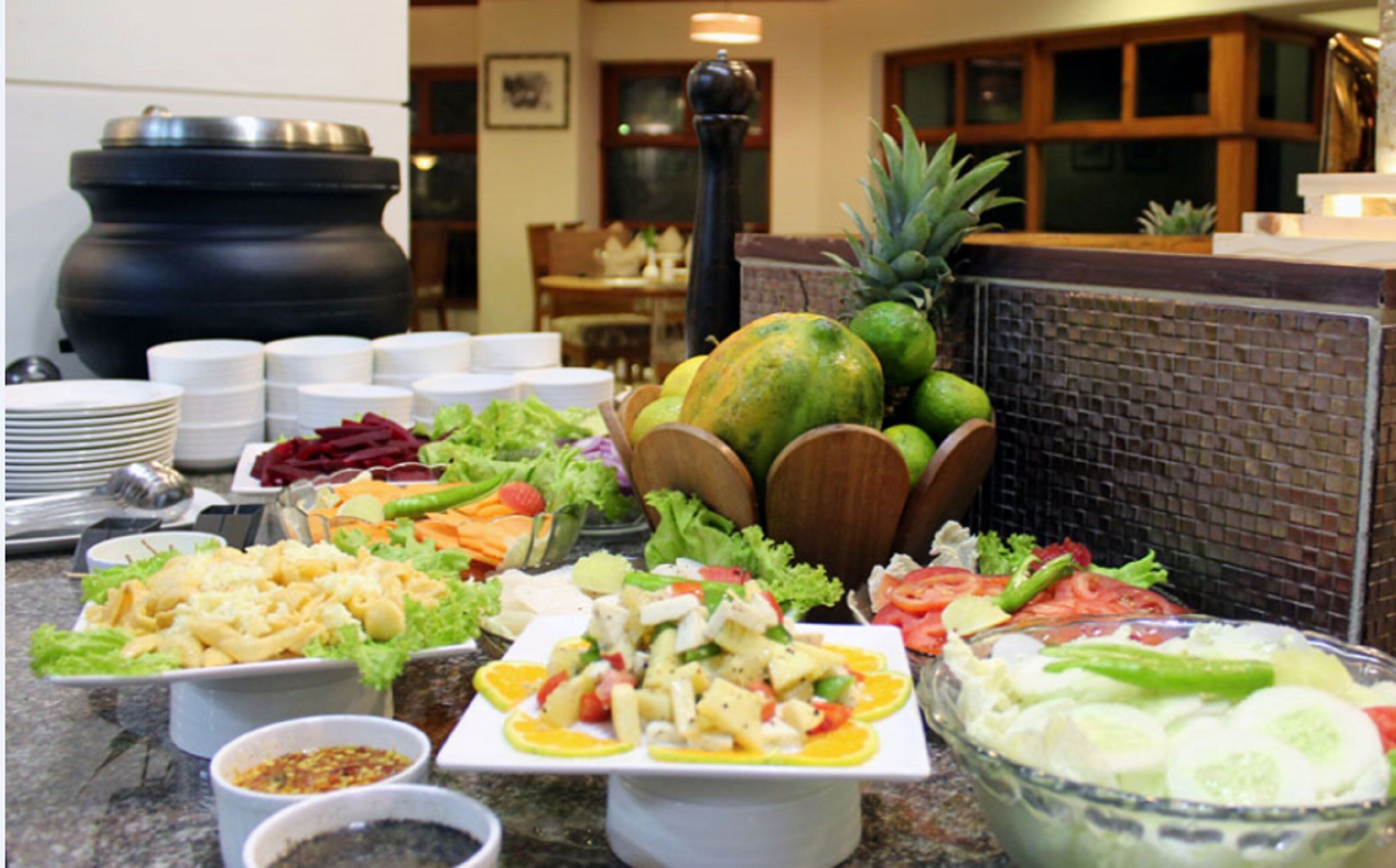 Una mesa de bufé con diversos platos, como ensaladas, frutas y mariscos.
