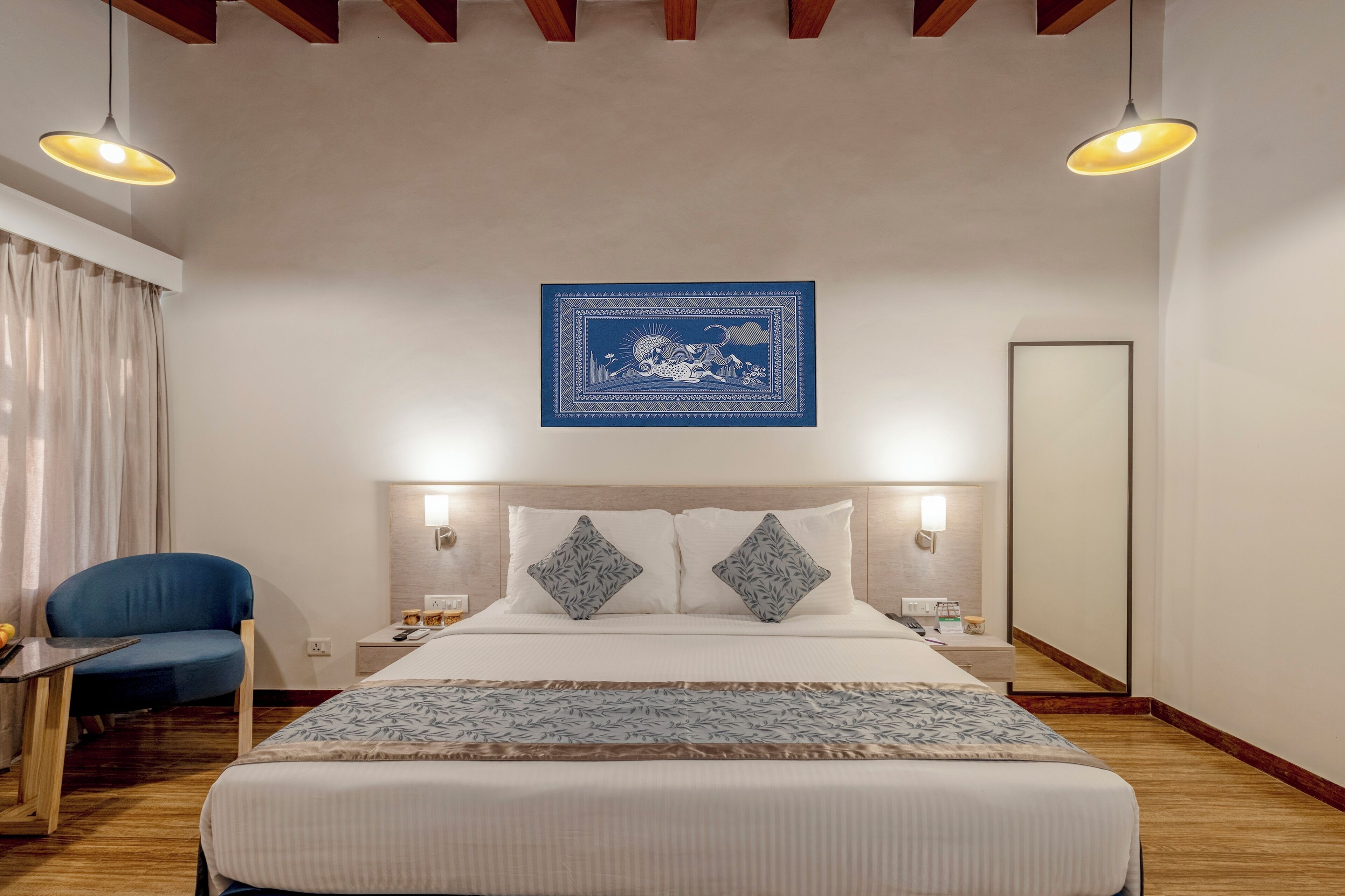 Una habitación de hotel con una cama grande, dos mesitas de noche, una silla y una obra de arte en la pared.