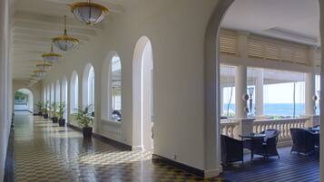 A long corridor with checkered flooring, arched ceilings, and potted plants.