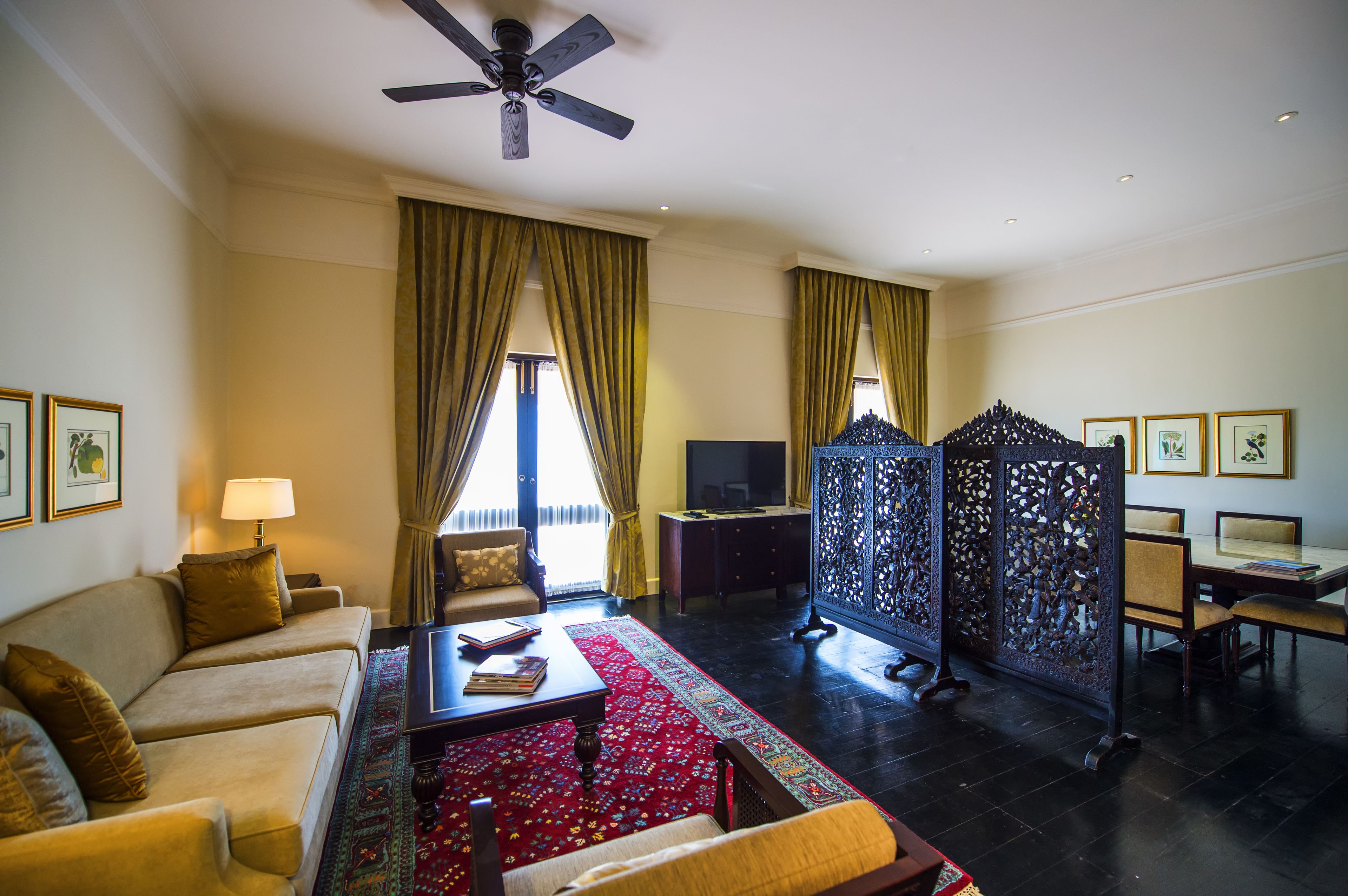 A living room with a sofa, coffee table, TV, and a partition with intricate designs.