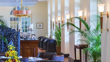 Un hall d’hôtel comprenant un comptoir d’accueil, un espace salon et des plantes décoratives.