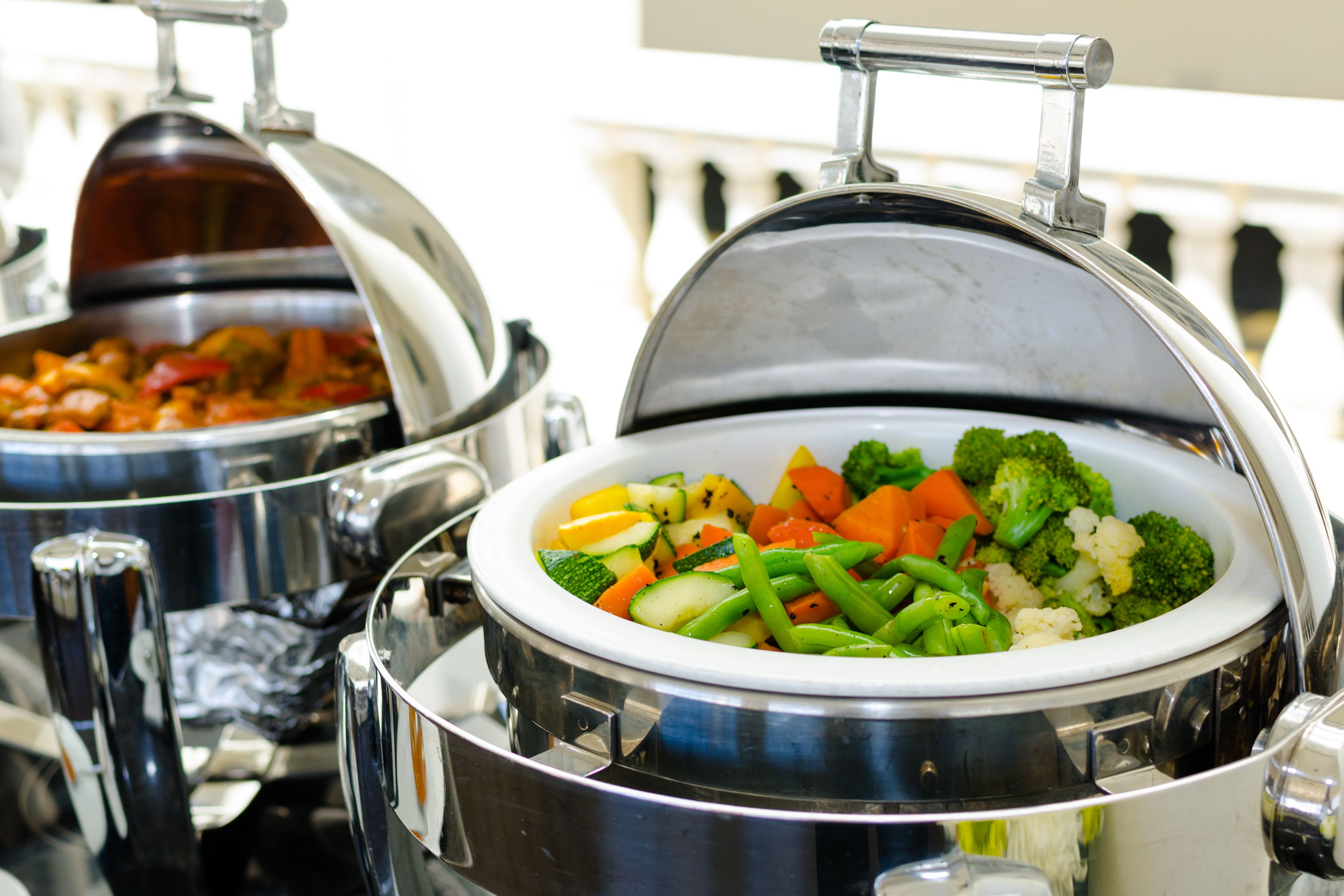 Two covered food dispensers with a variety of vegetables.