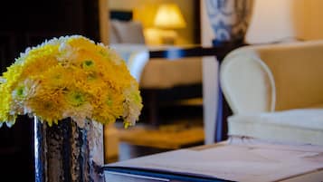 A room with a vase of yellow flowers on a table, a lamp, and a chair.