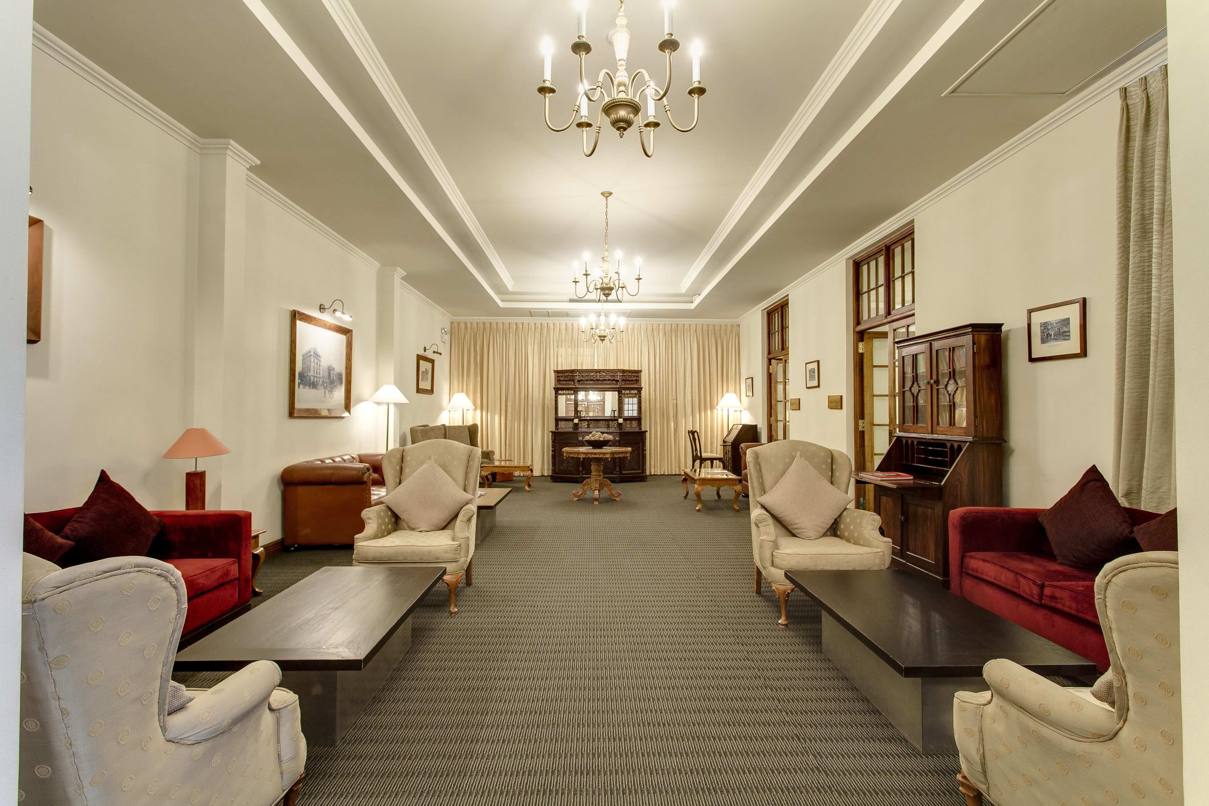 A spacious living room with a large chandelier, two sofas, a coffee table, and a wooden cabinet.