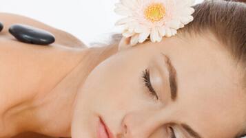 A person receiving a back massage with black stones.
