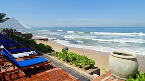 Un hotel frente a la playa con sillones de descanso y un macetero grande.