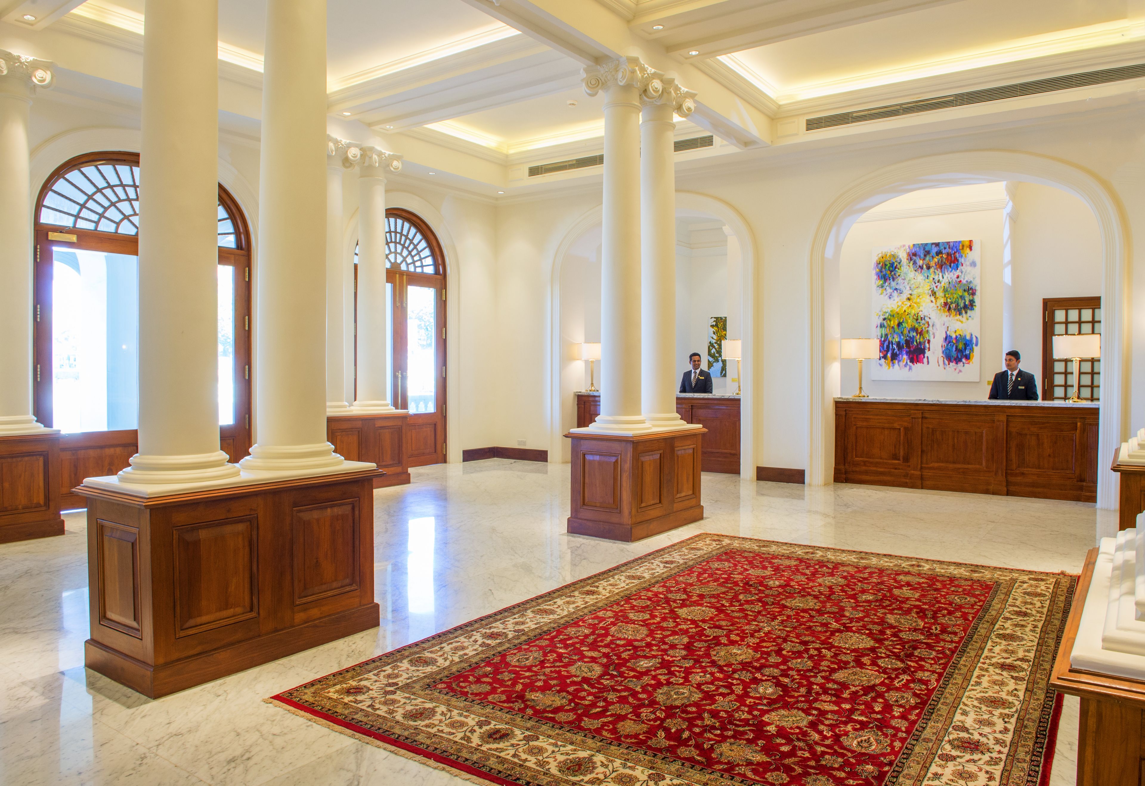 A spacious lobby with high ceilings, large columns, and a red patterned carpet.