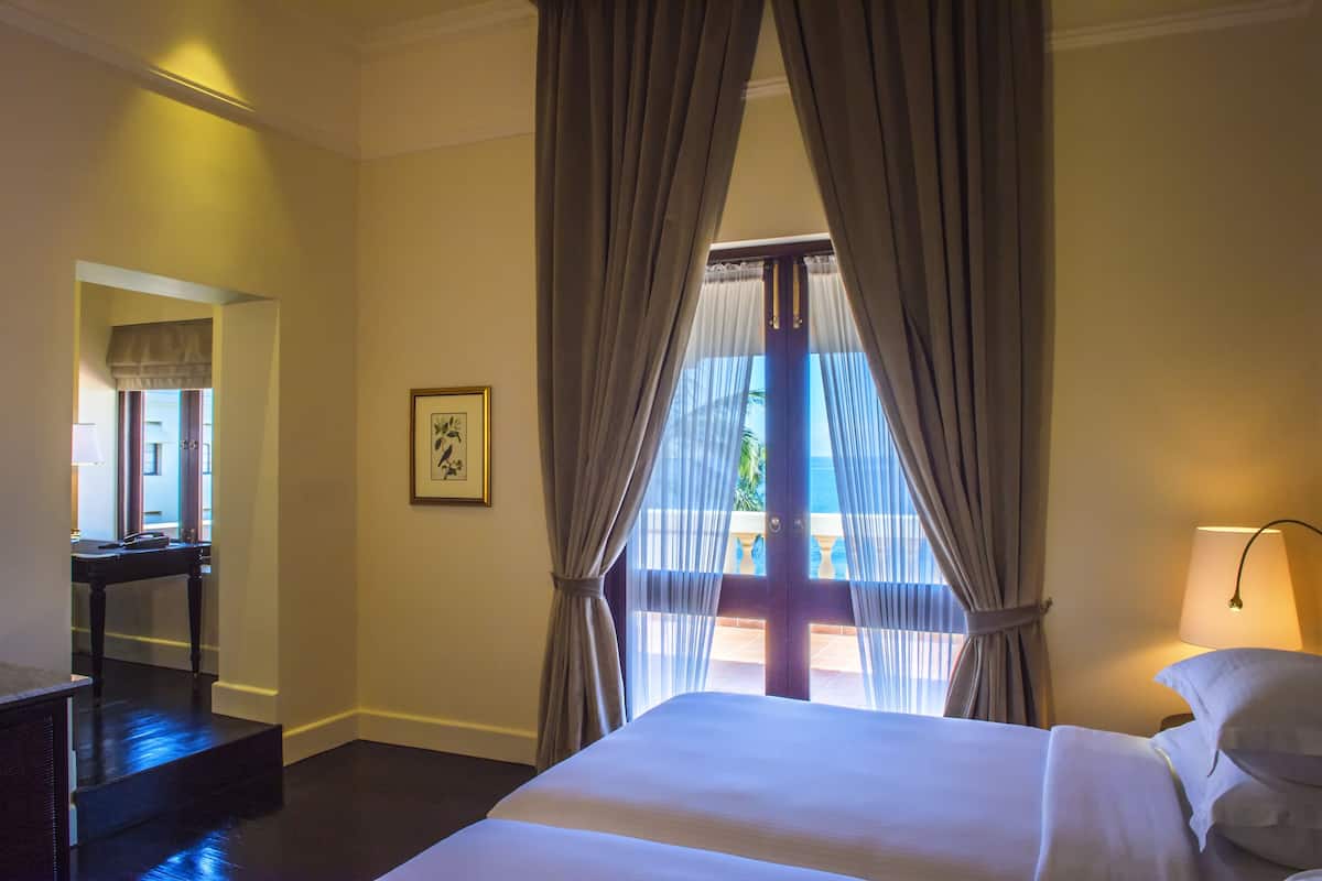 A hotel room with a bed, a desk, a chair, and a window with curtains.