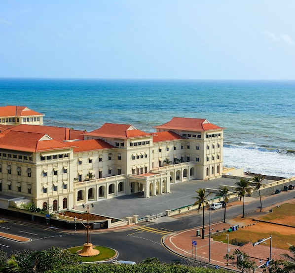 A large, multi-story building with a red-tiled roof, located near a body of water.