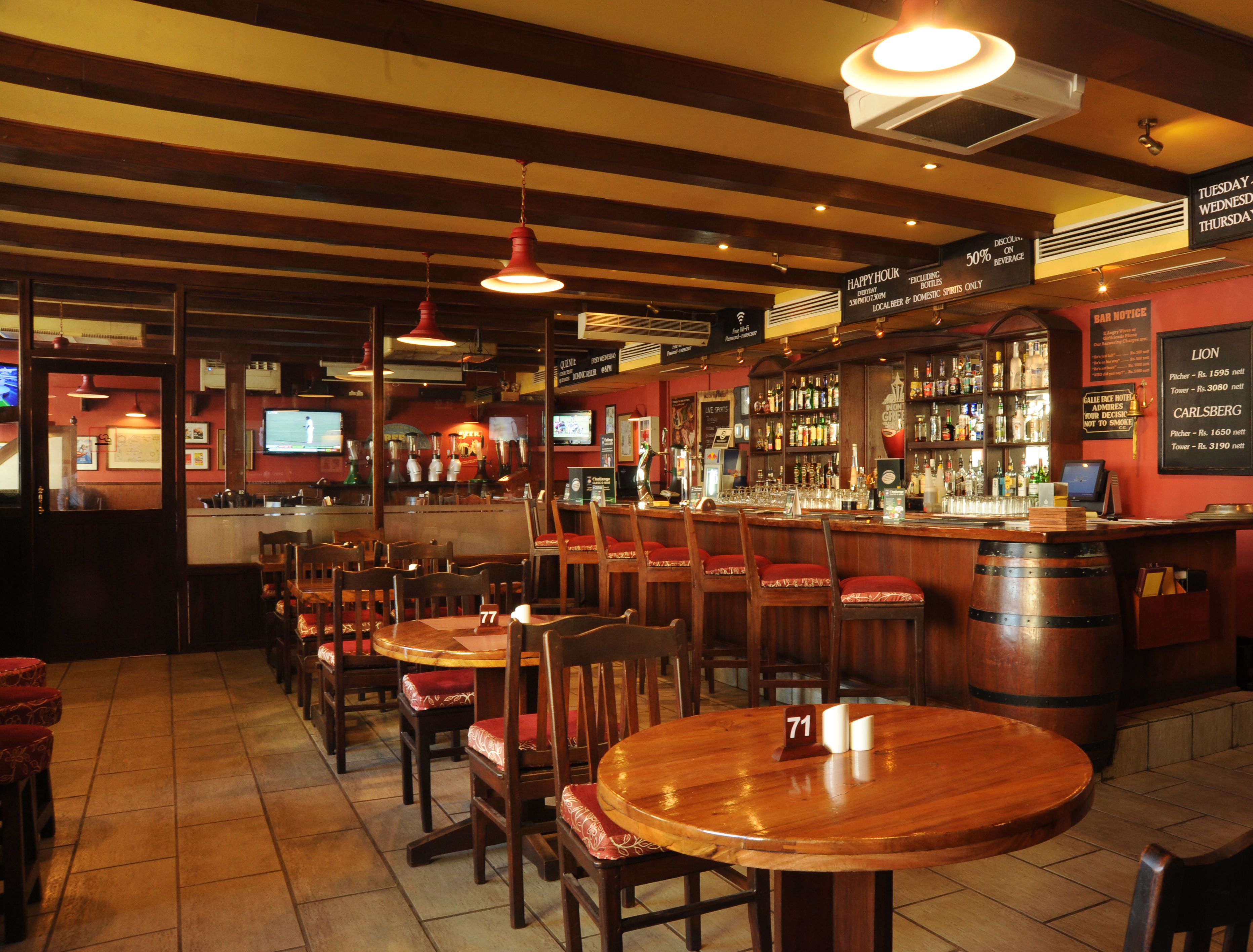 Eine Bar mit Holztischen und -stühlen, einer Theke voller Flaschen und einer Speisekarte.