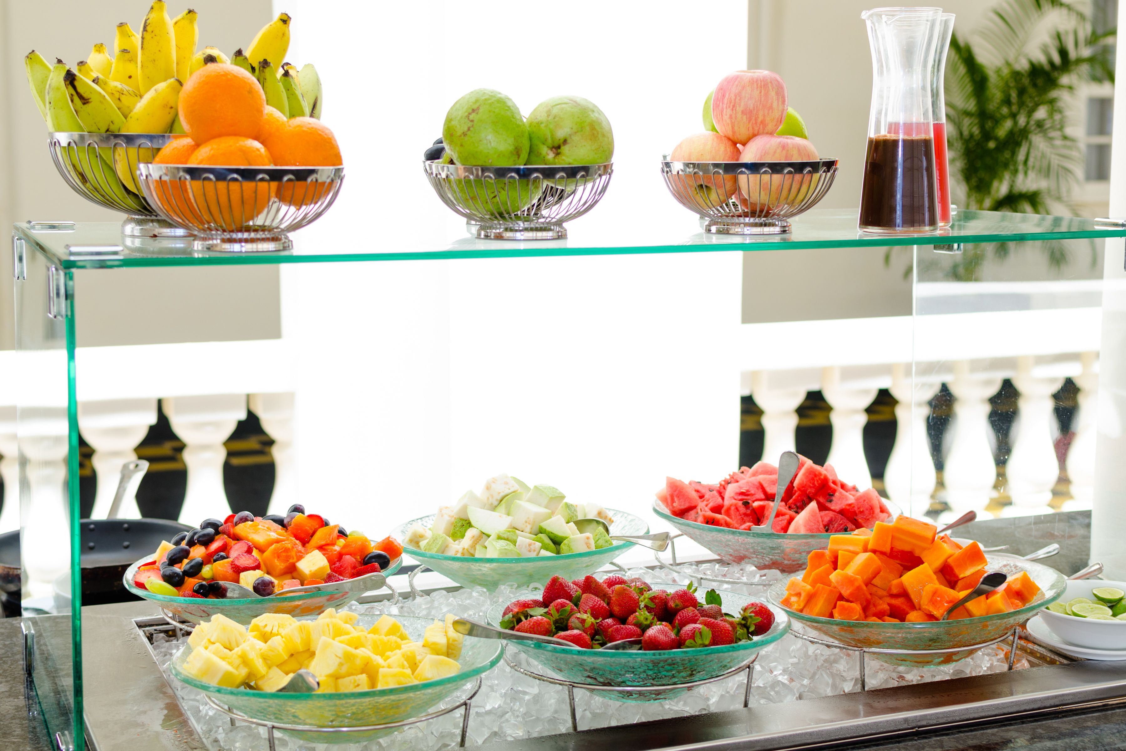 A buffet with various fruits and a pitcher of juice.