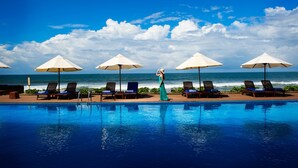 Zona junto a la piscina con sillas de descanso y sombrillas, con vista al océano.