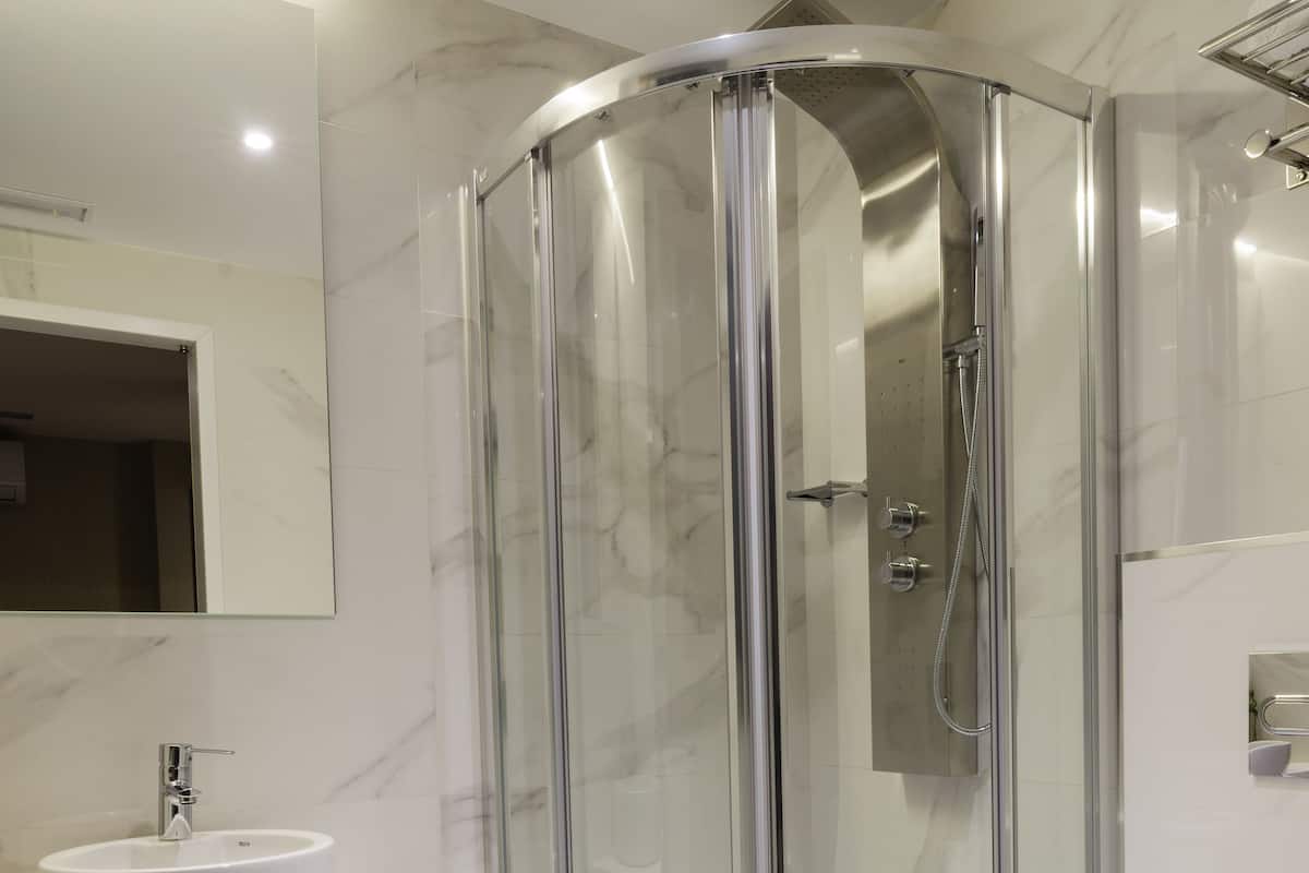 Un baño moderno con ducha envuelta en vidrio, un lavamanos blanco y un inodoro.