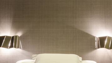 A hotel room with a bed, pillows, and a wall-mounted artwork depicting boats.
