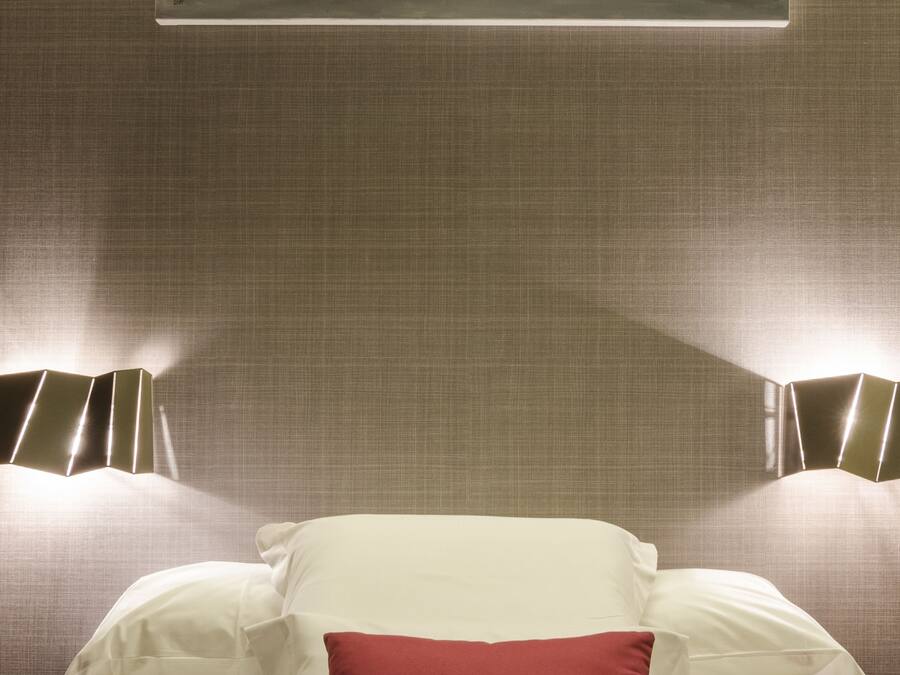 A hotel room with a bed, pillows, and a wall-mounted artwork depicting boats.