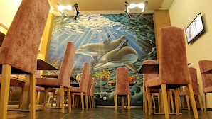 A restaurant with pink chairs and a mural of dolphins on the wall. - Agua de Mar Hotel Boutique (Vigo)