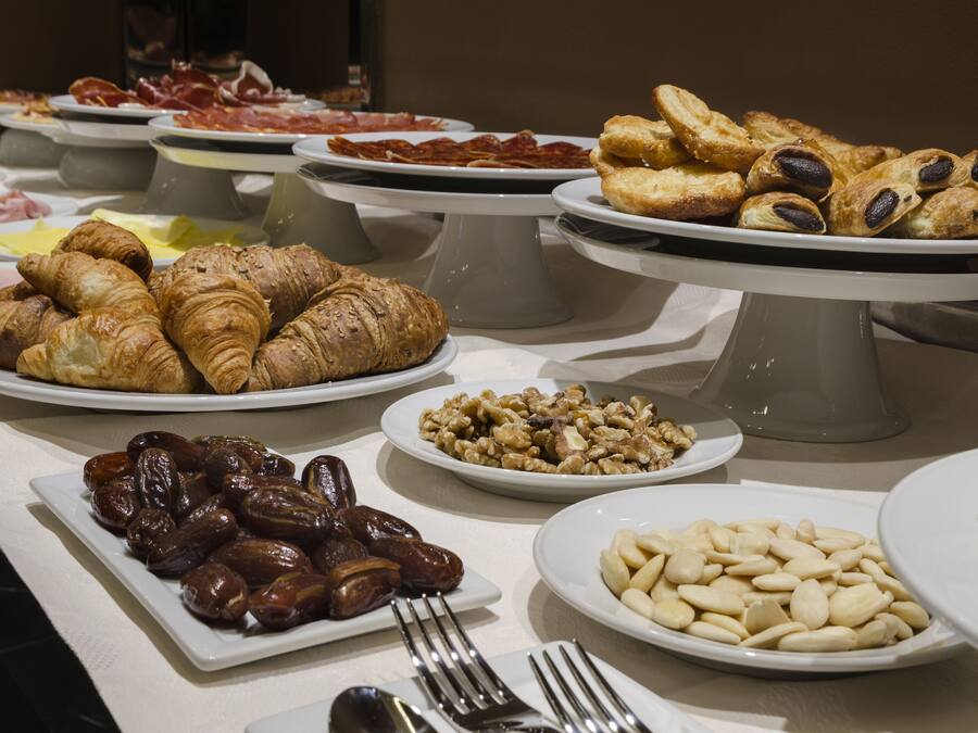 Buffet com diversos alimentos, incluindo doces, carnes e frutos a secum.