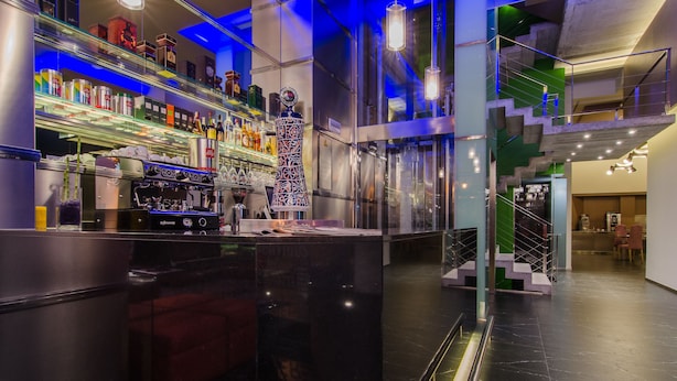 A modern bar area with a coffee machine, shelves of bottles, and a staircase with a green accent. - Agua de Mar Hotel Boutique (Vigo)