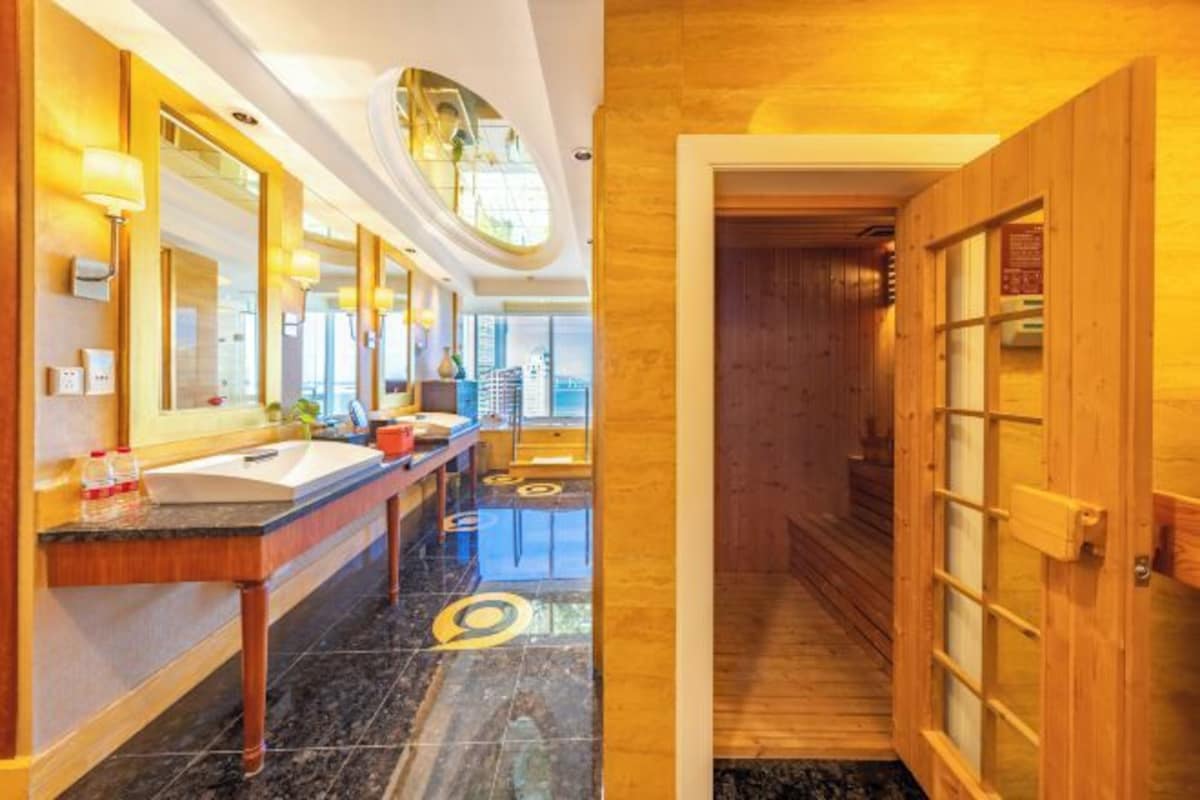 A modern bathroom with a long vanity, large mirrors, and a wooden door.