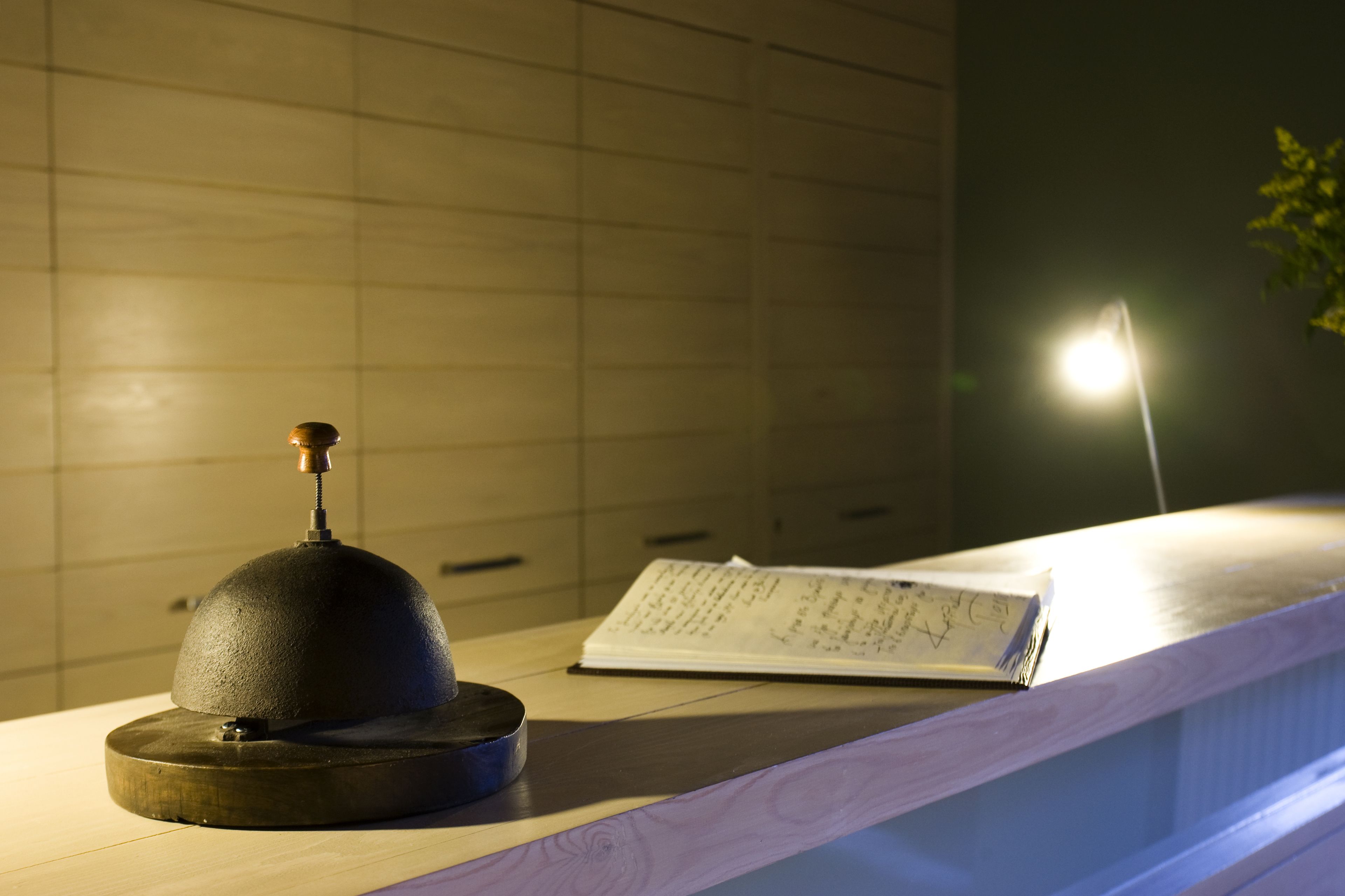 A wooden reception desk with a metal bell and a notepad.