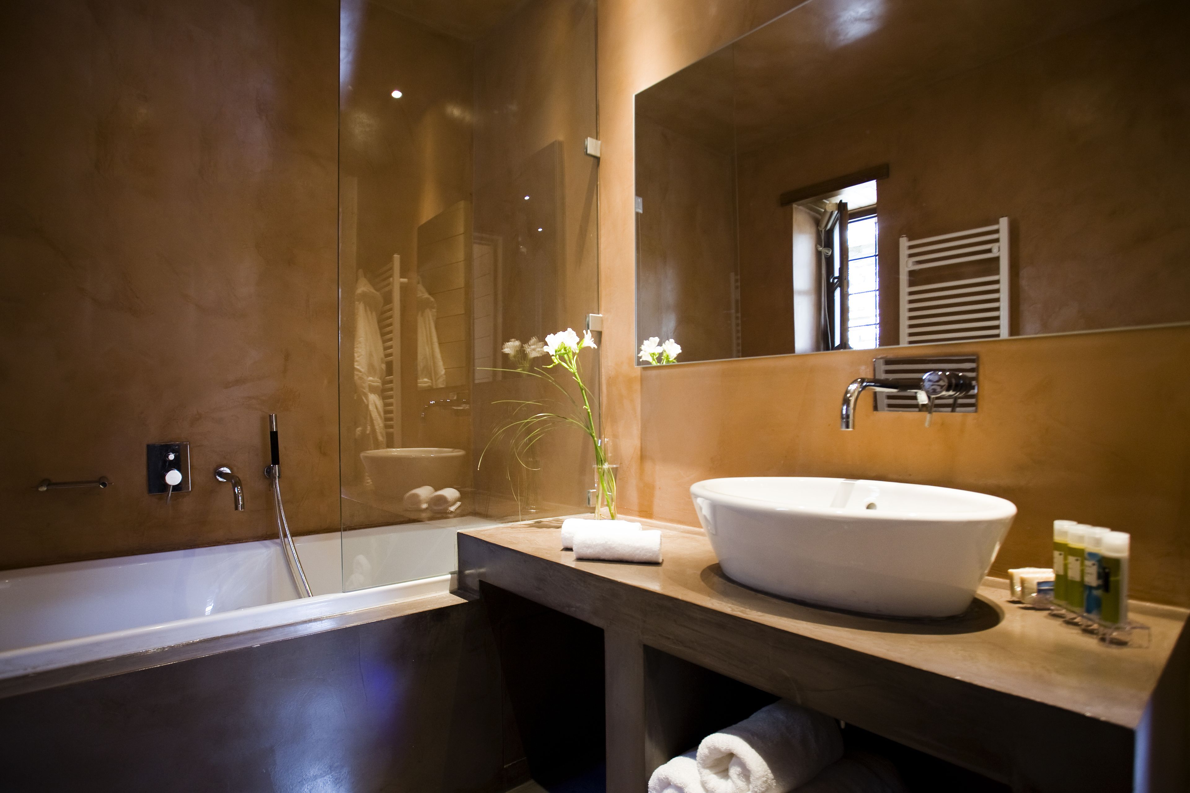 A modern bathroom with a large bathtub, a round sink, and a mirror above the sink.