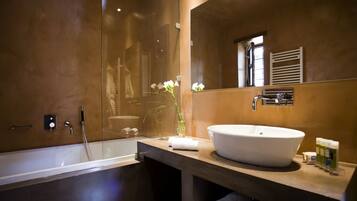A modern bathroom with a large bathtub, a round sink, and a mirror above the sink.