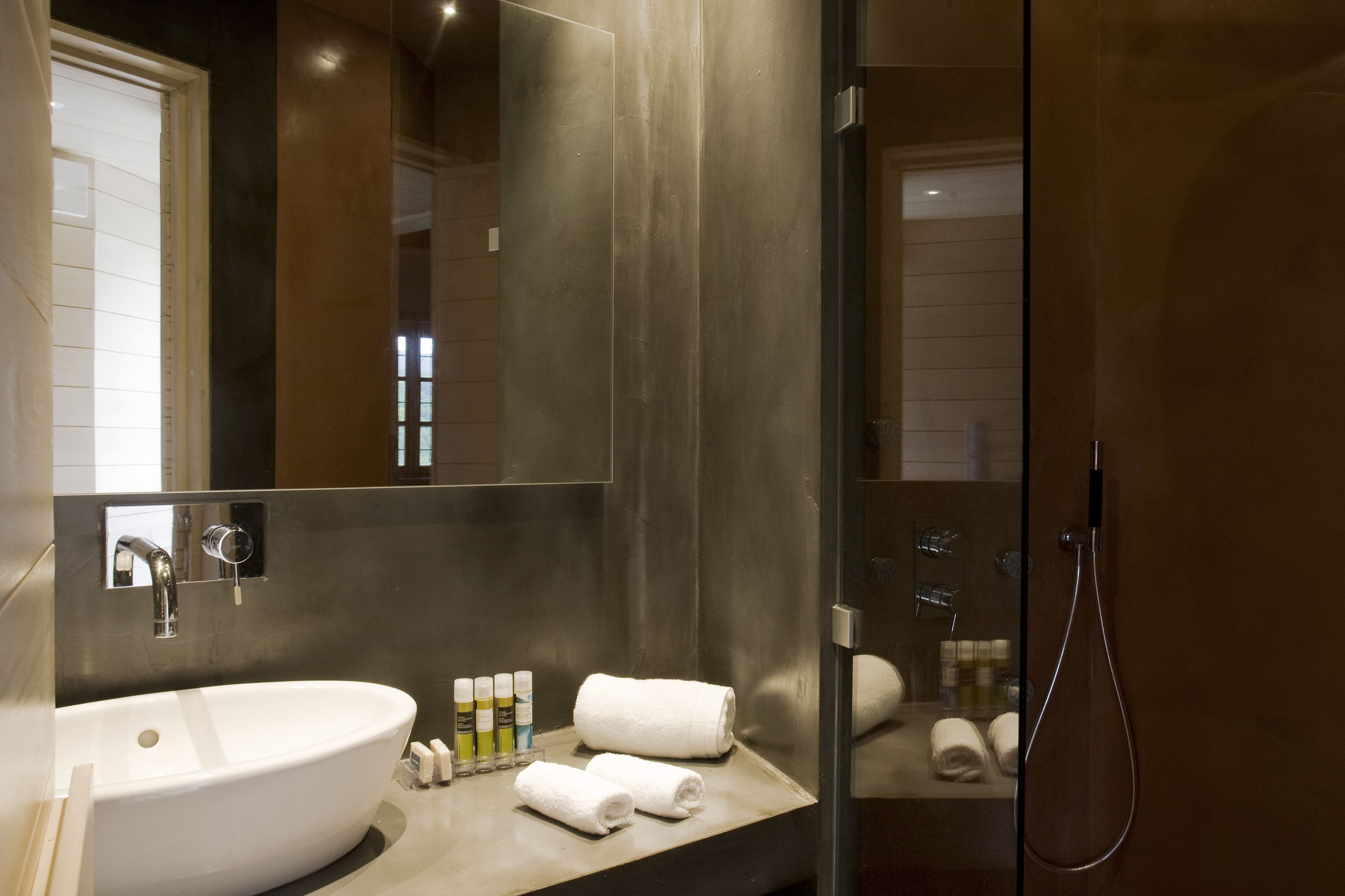Un baño moderno con un lavamanos grande de color blanco, un espejo y una ducha con mampara de vidrio.