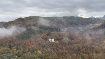 A mountain landscape with a traditional building surrounded by autumn foliage.