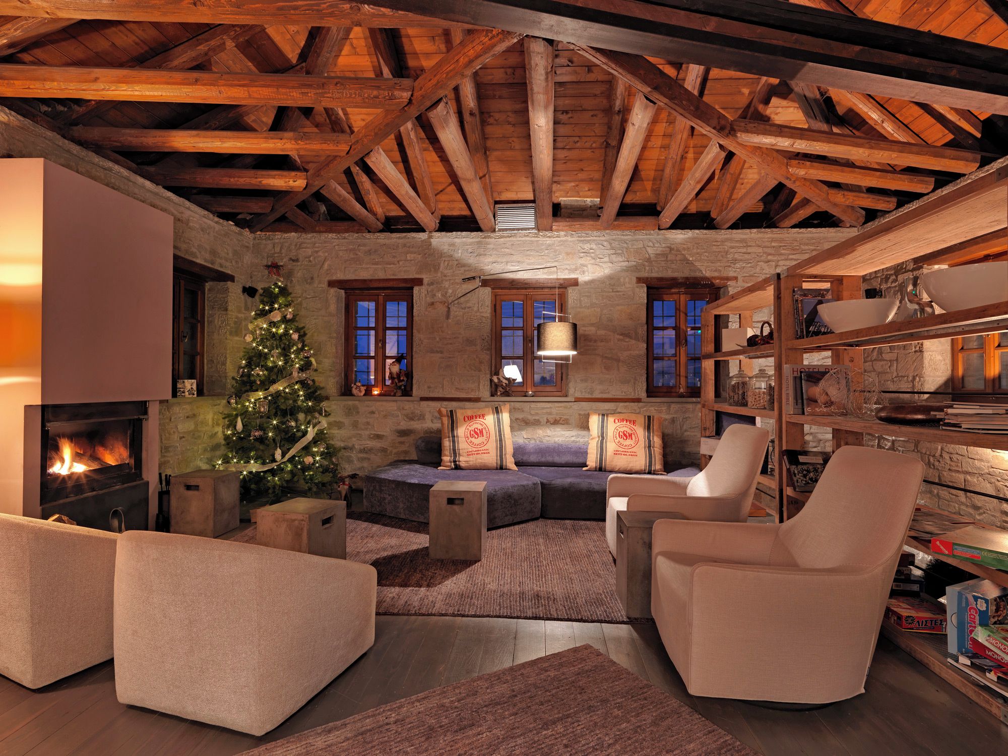 A cozy living room with a fireplace, a Christmas tree, and a stone wall.