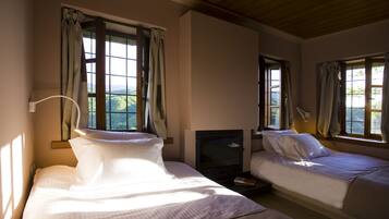 A hotel room with two beds, a TV, and windows with curtains.