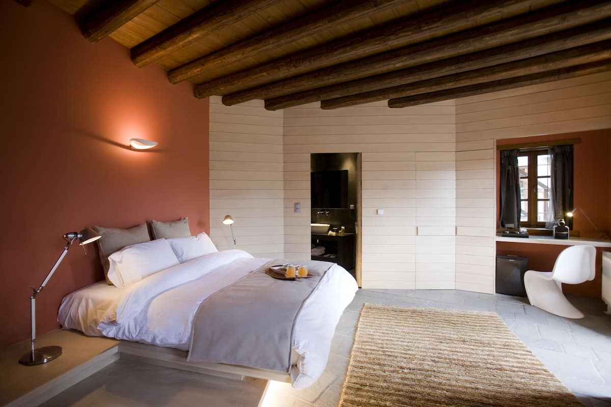 Un dormitorio con cama, lámpara de noche y un escritorio con silla.