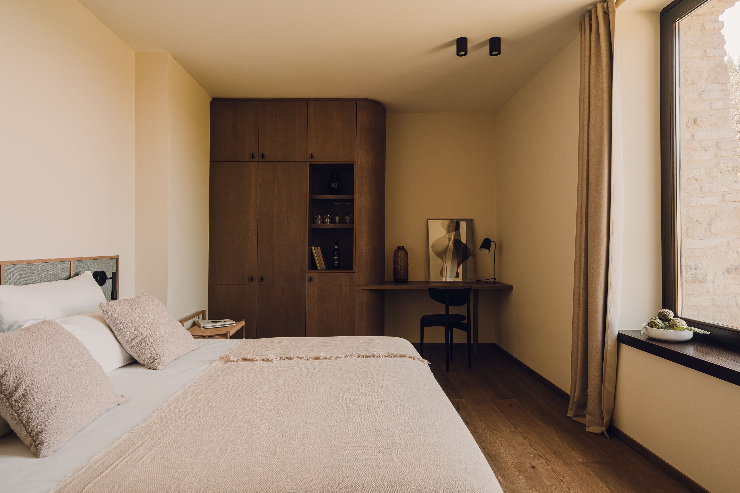 A bedroom with a bed, a desk, and a wardrobe.
