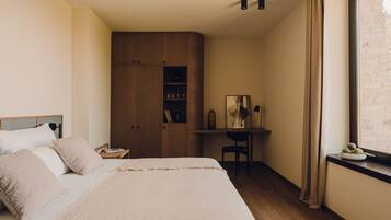 A bedroom with a bed, a desk, and a wardrobe.