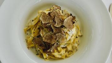 A white plate with fettuccine pasta topped with shaved truffles.