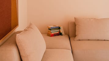 A modern living room with a beige sofa, a small stack of books, and a hanging light fixture.