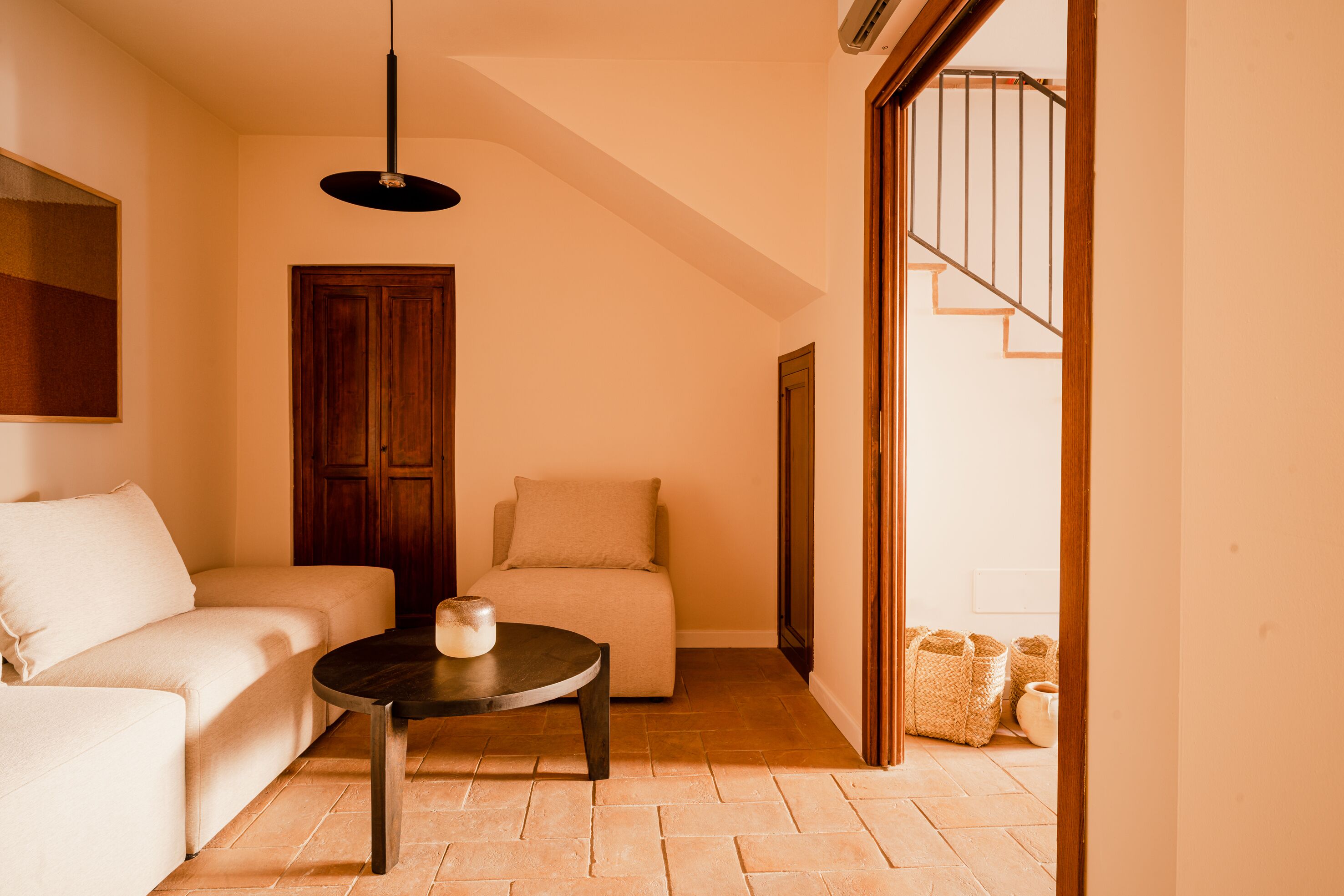 A living room with a sofa, a coffee table, a door, and a staircase leading to another room.
