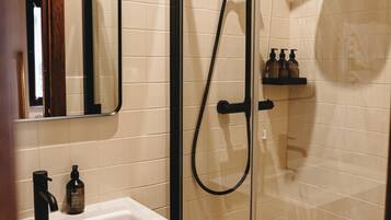 A bathroom with a glass-enclosed shower, a white sink, and a mirror.