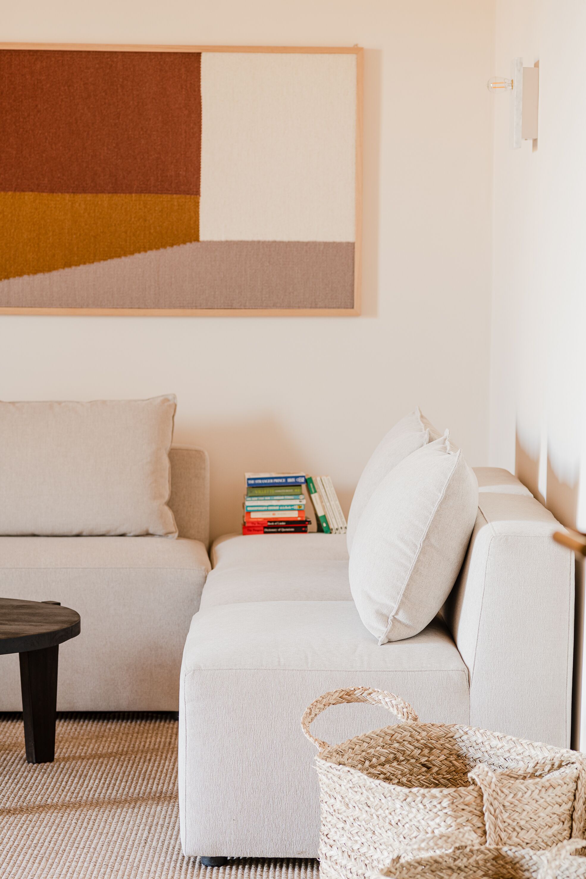 A modern living room with a light-colored sofa, a small coffee table, and a woven basket on the floor.