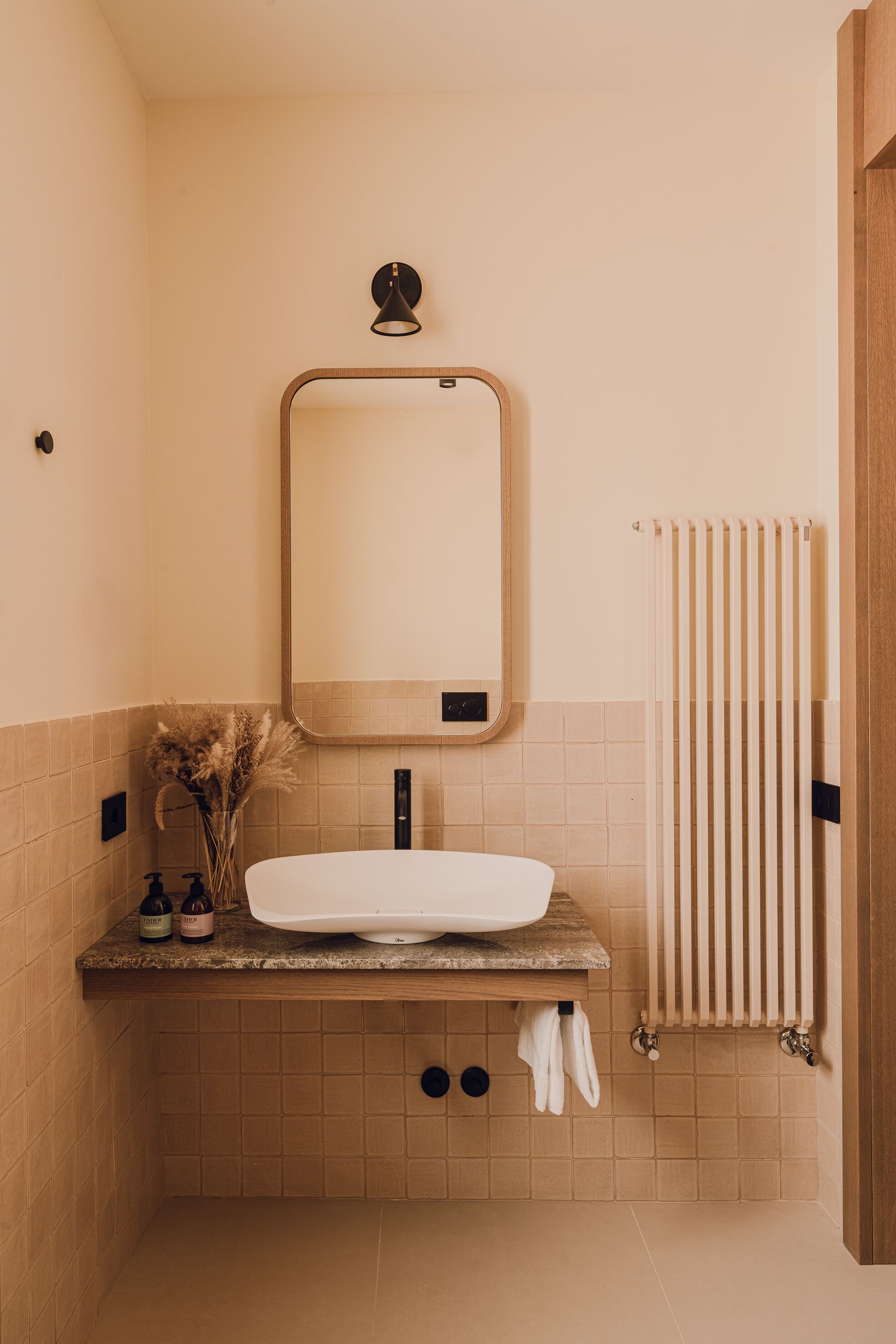 A bathroom with a white sink, a mirror, a towel rack, and a radiator.