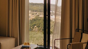 Une pièce dotée d’une grande porte-fenêtre coulissante donnant sur un paysage extérieur magnifique, d’un canapé, d’un fauteuil et d’une petite table sur laquelle sont posés des livres.