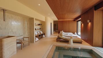 A modern spa room with a glass-enclosed hot tub, wooden furniture, and a large window providing natural light.