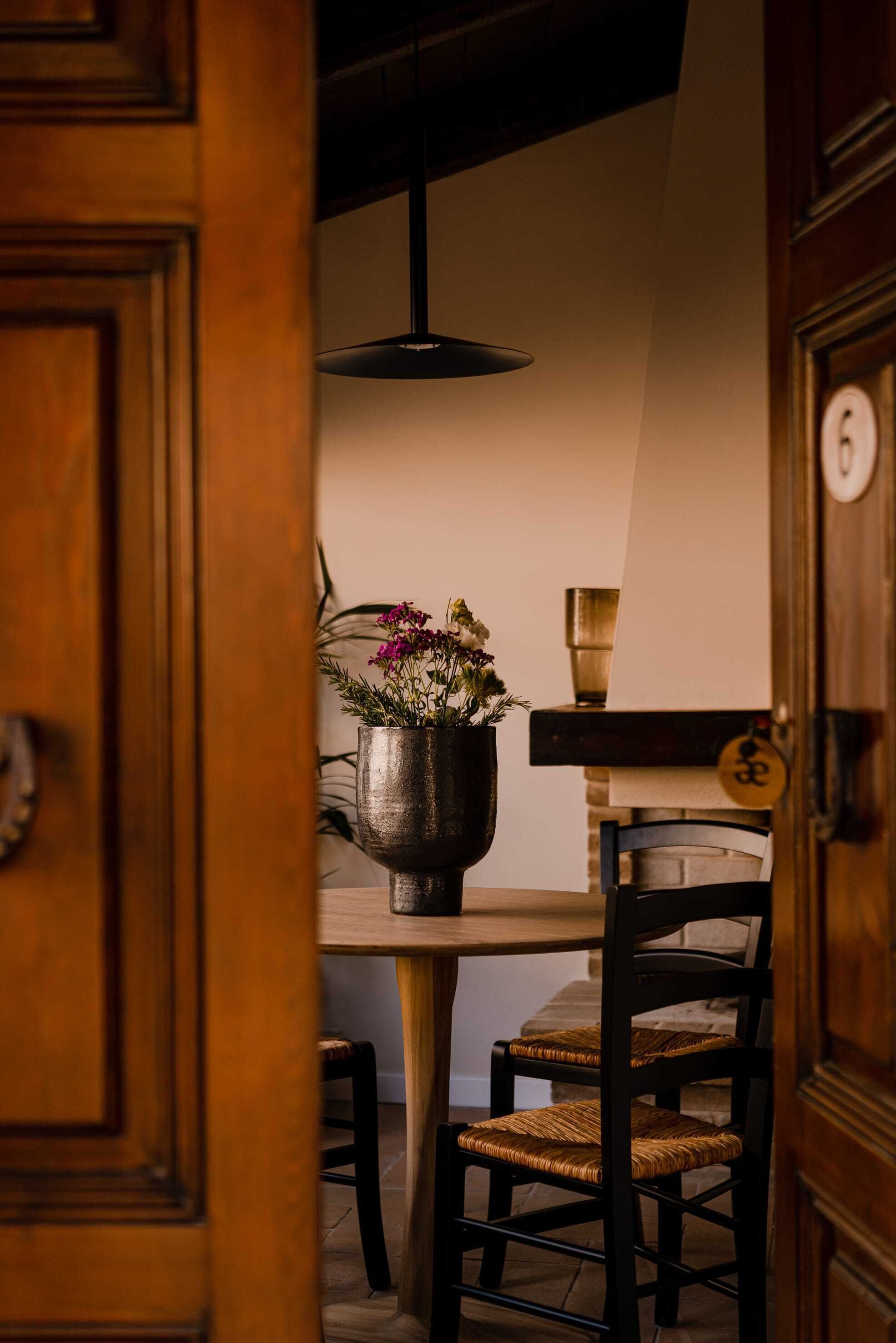 A wooden door leading to a dining area with a table, chairs, and a hanging light fixture.
