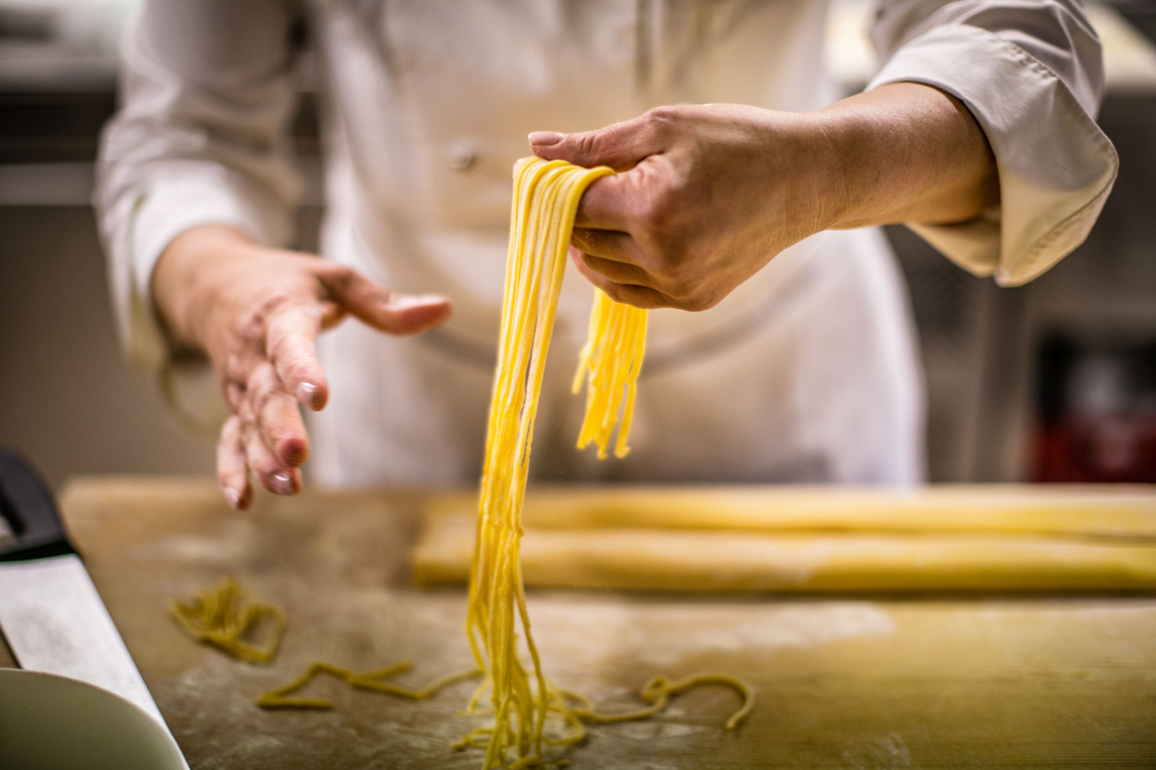 Una persona preparando pasta sobre una superficie de madera.