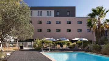 Ett hotell med en swimmingpool, solstolar och parasoller.