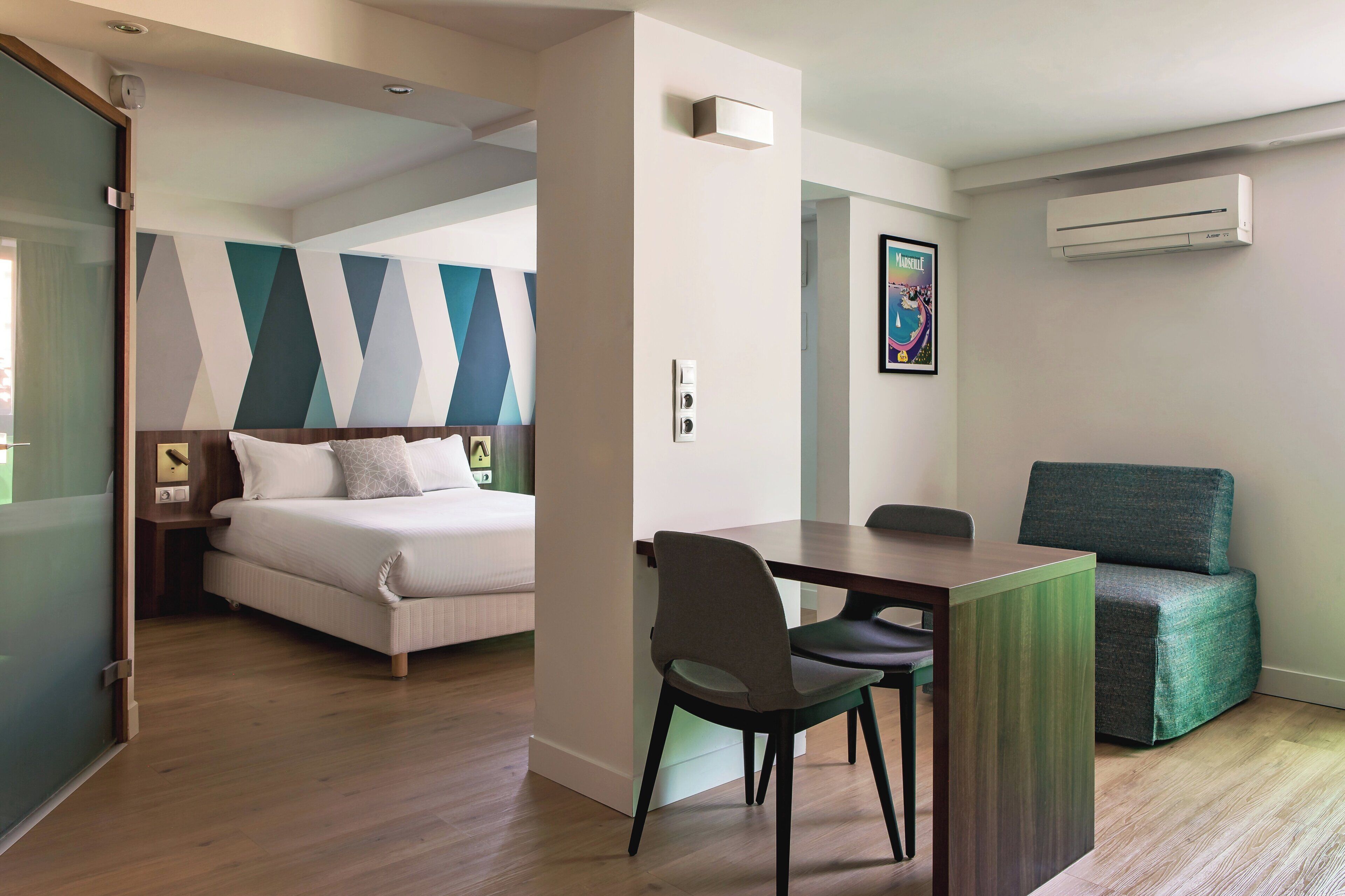 A hotel room with a bed, a desk, a chair, and a sofa.